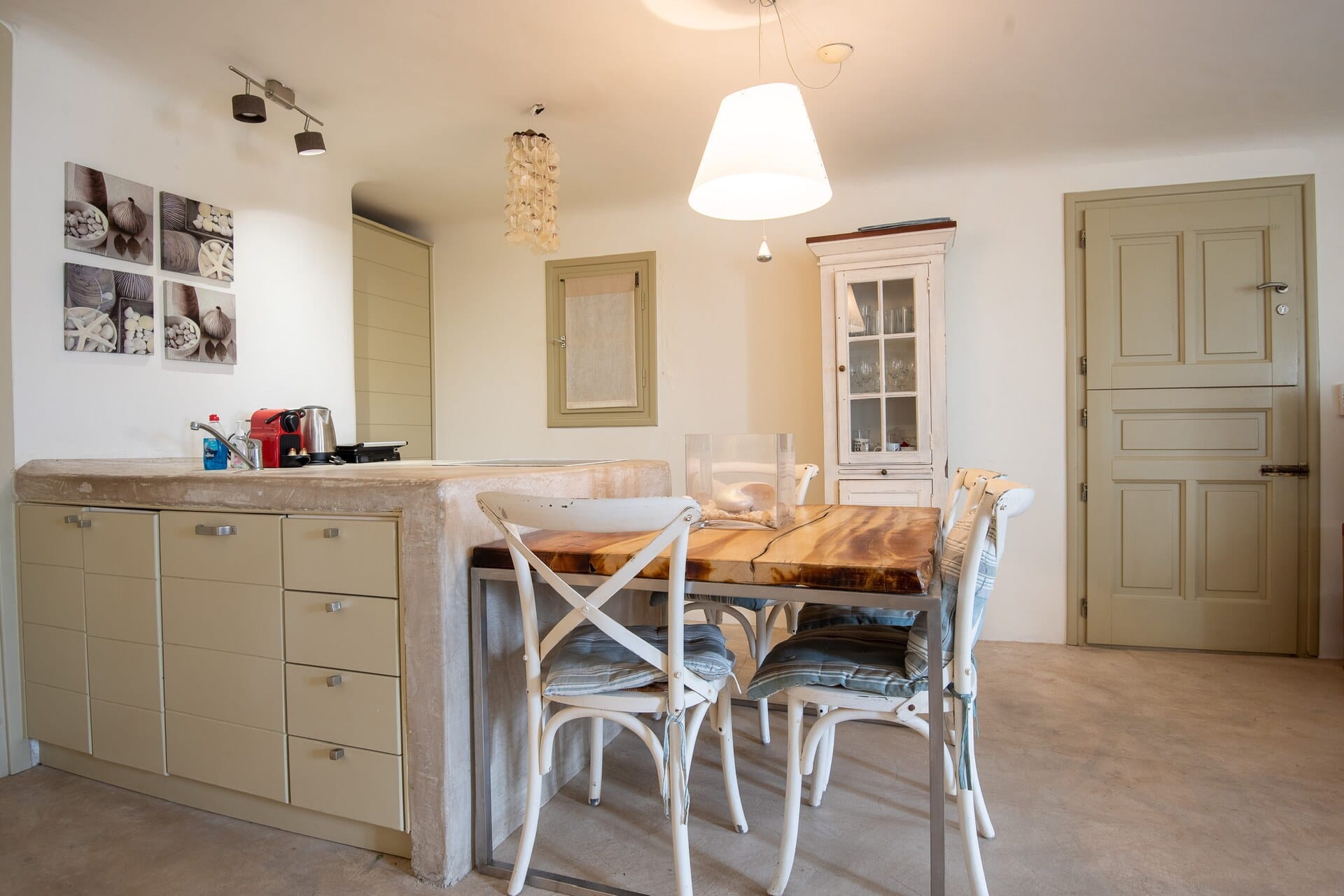 Open-plan dining and kitchen area with a wooden table and white chairs at Mykonos Ilios House